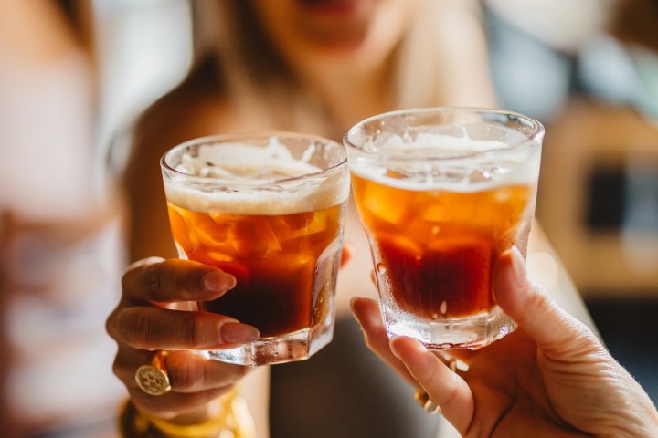 a close up of a person holding a glass of beer on a table