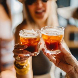 a close up of a person holding a glass of beer on a table