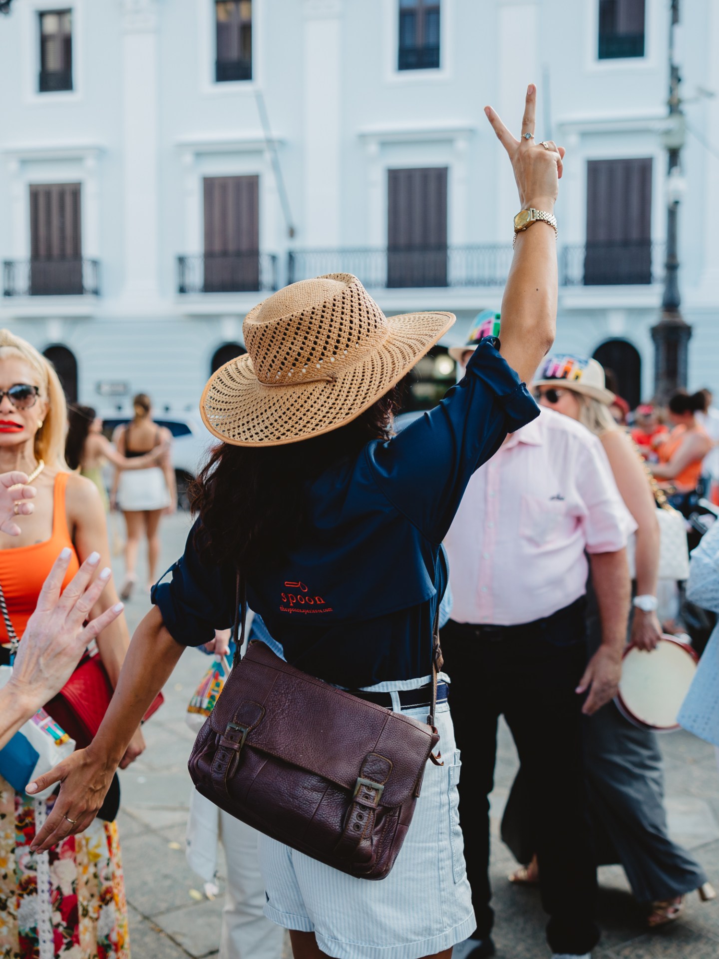 Group of people in hats socializing outdoors in a plaza.