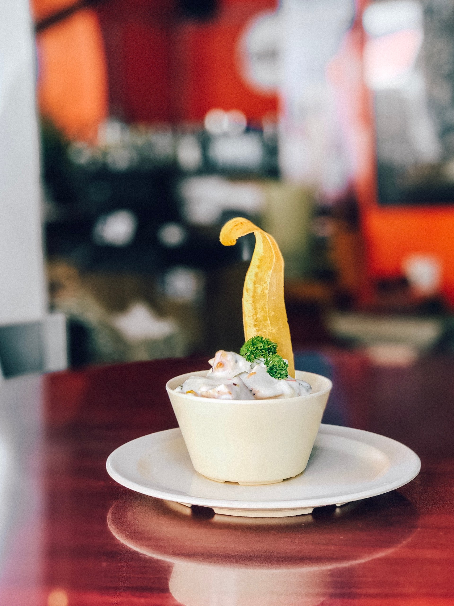 Cup of creamy dessert with garnish and plantain chip on a plate.