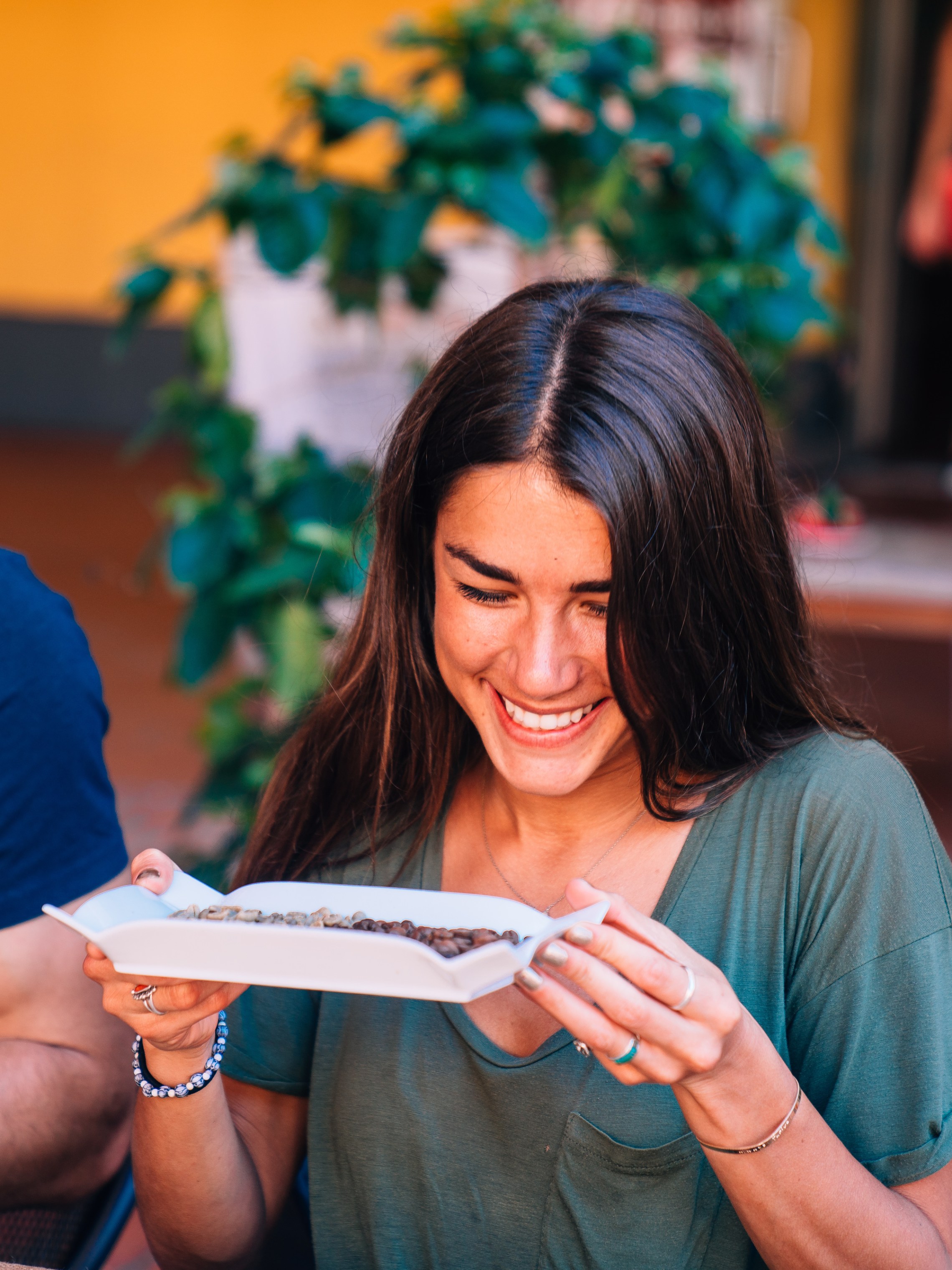 Smiling woman holding a food tray at a table with friends outdoors.