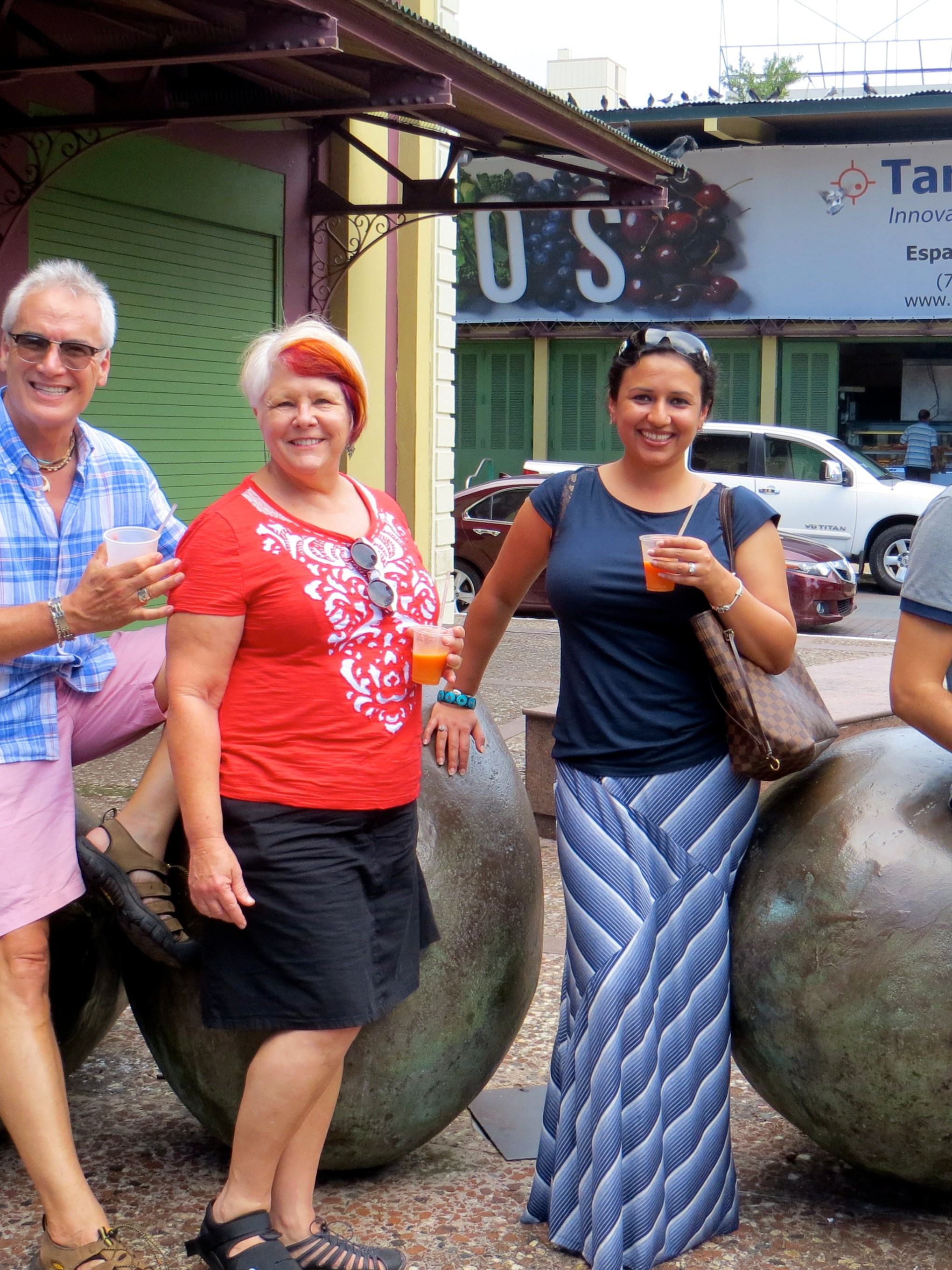 Four people smiling and holding drinks, posing on large spherical sculptures.