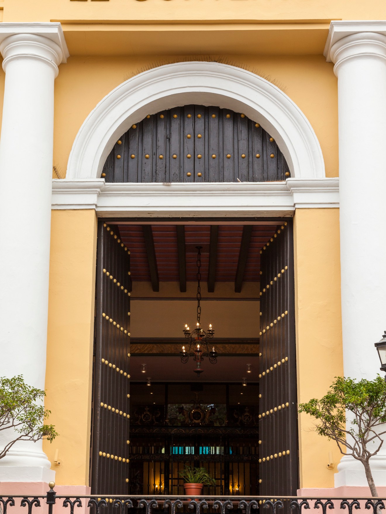 Entrance of El Convento, featuring large wooden doors, columns, and visible chandelier inside.