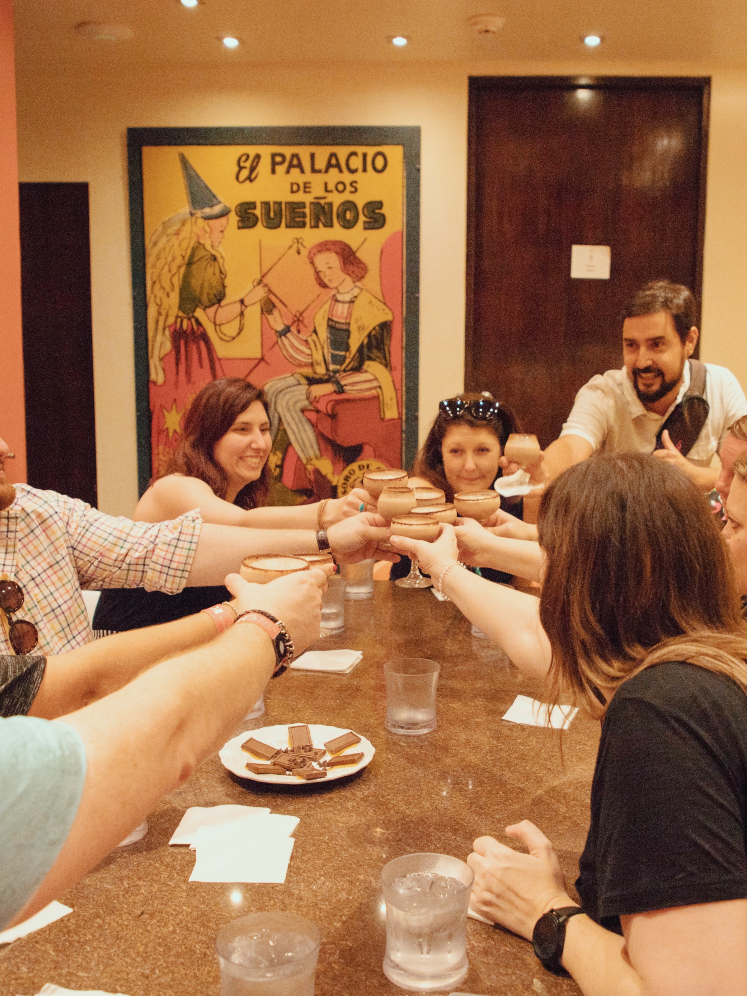 People sitting around a table toasting with cups indoors.