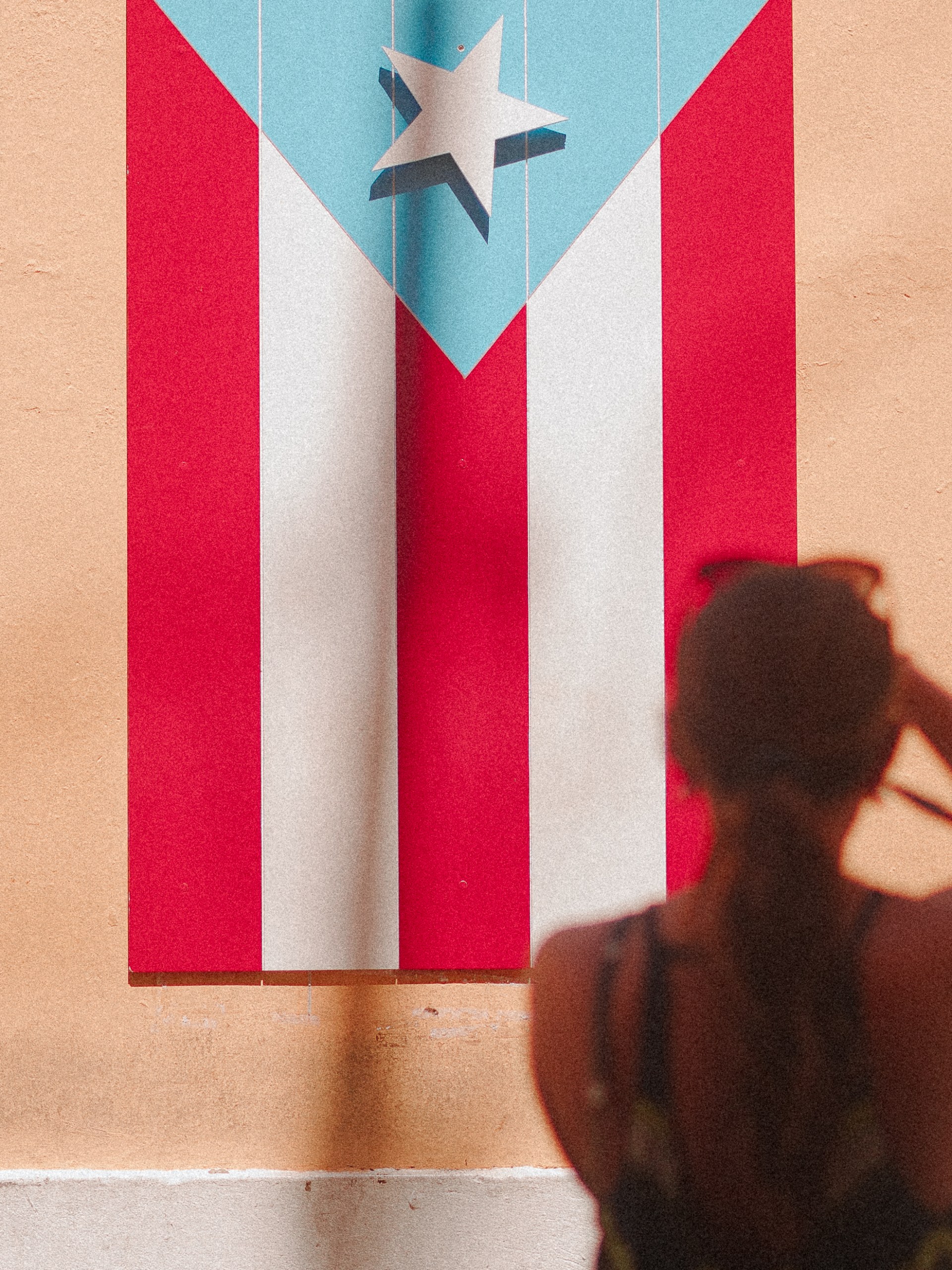 Person facing colorful mural with star and stripes on wall.
