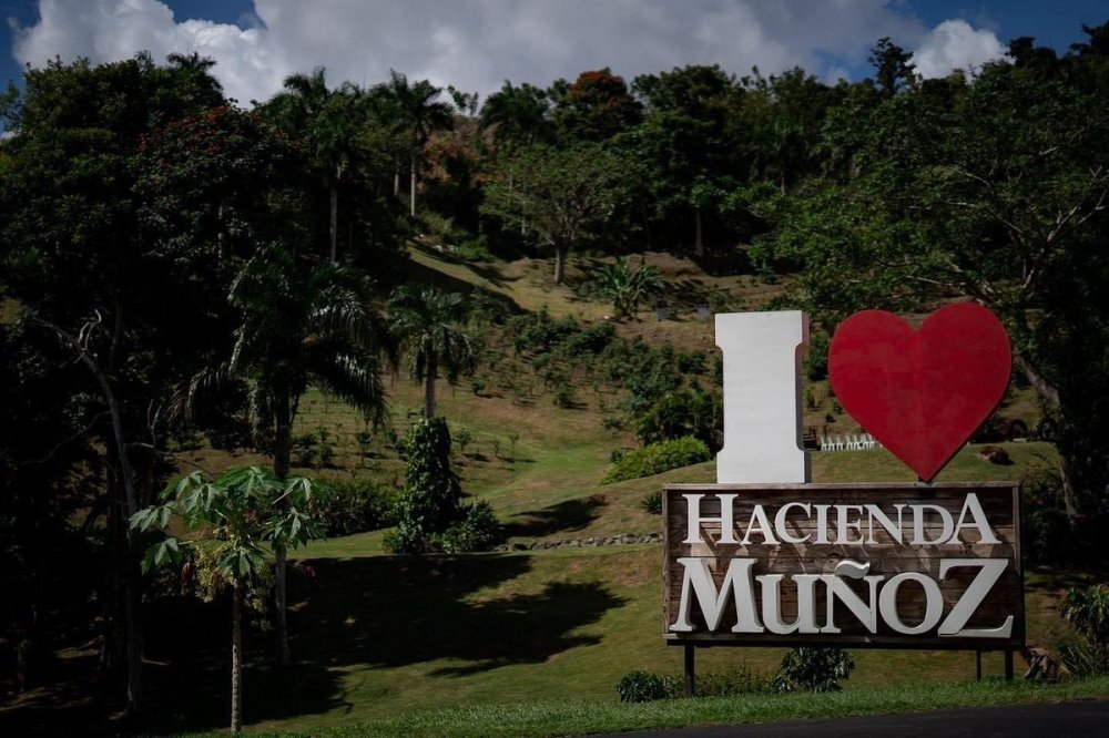 Sign reading 'I heart Hacienda Muñoz' amidst lush trees and hillside.