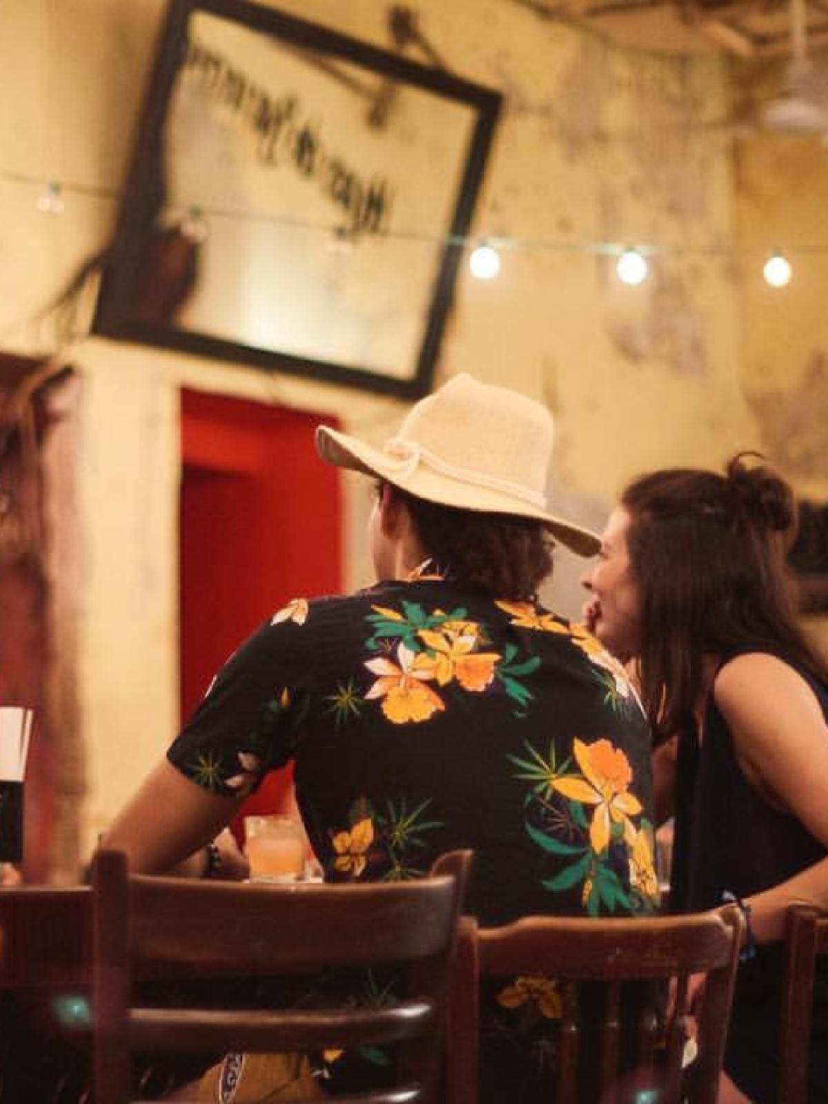 People enjoying conversation at a cozy bar with string lights and rustic decor.