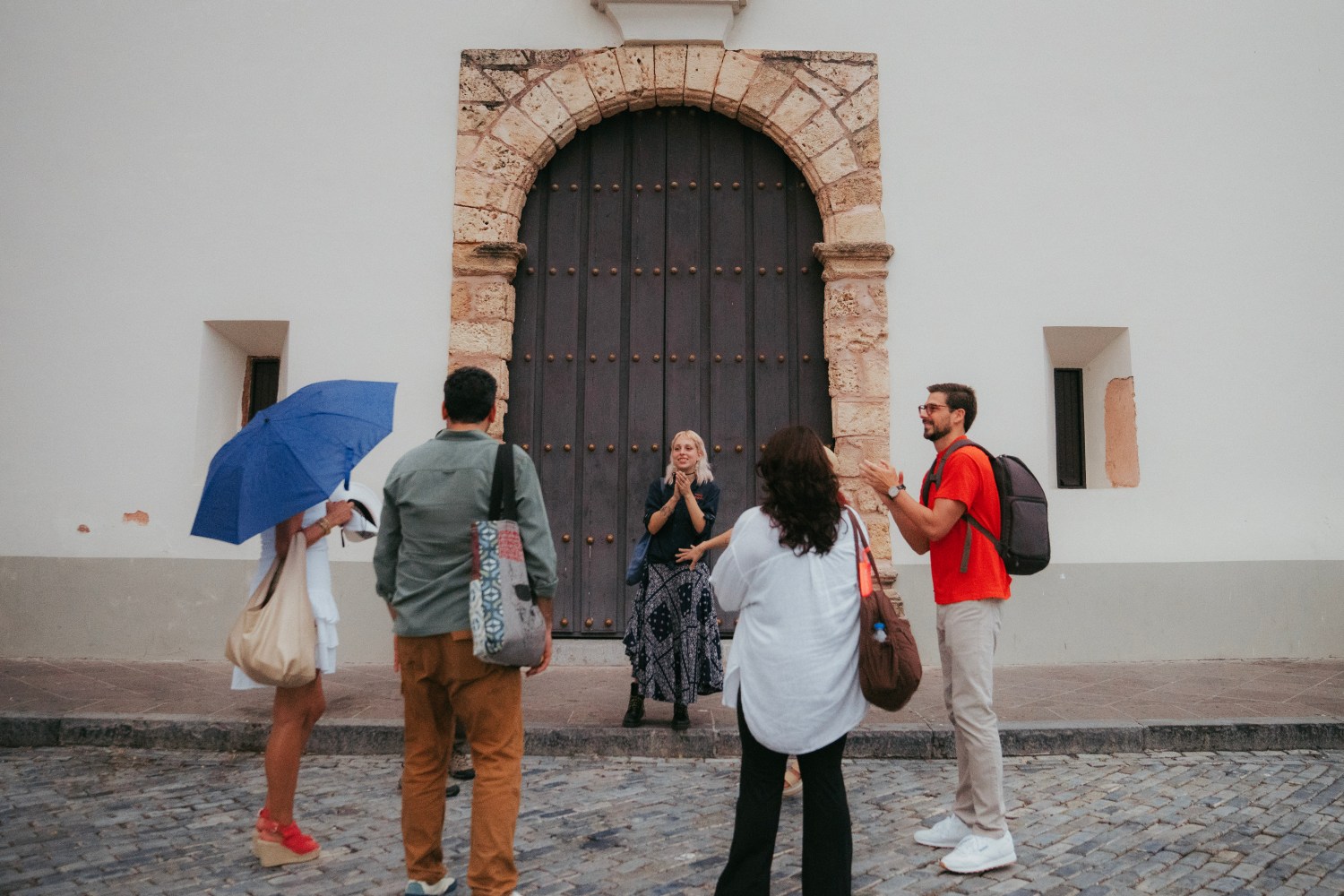 Tour group gathers outside historic stone door on a cobblestone street.