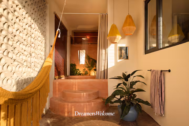 Stylish room with a yellow hammock, hanging lamps, plants, and textured walls.